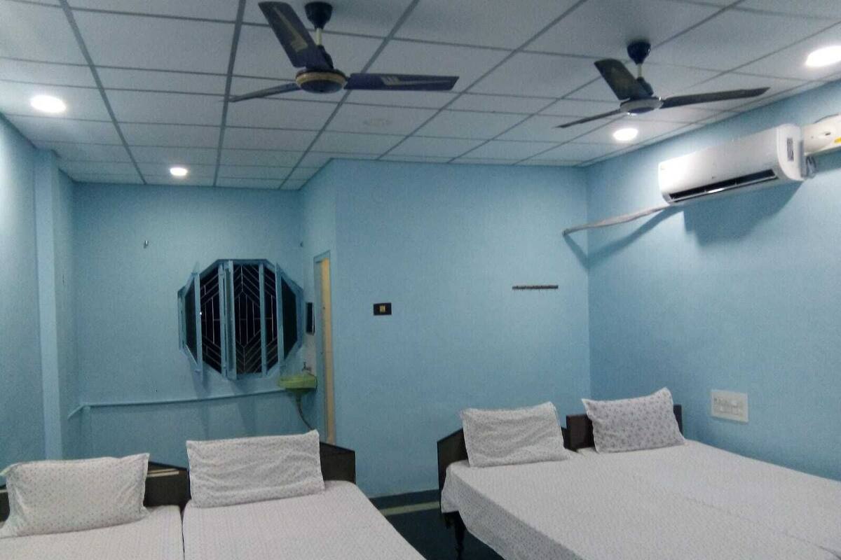 Una stanza con due letti, ventilatori a soffitto e condizionatore.