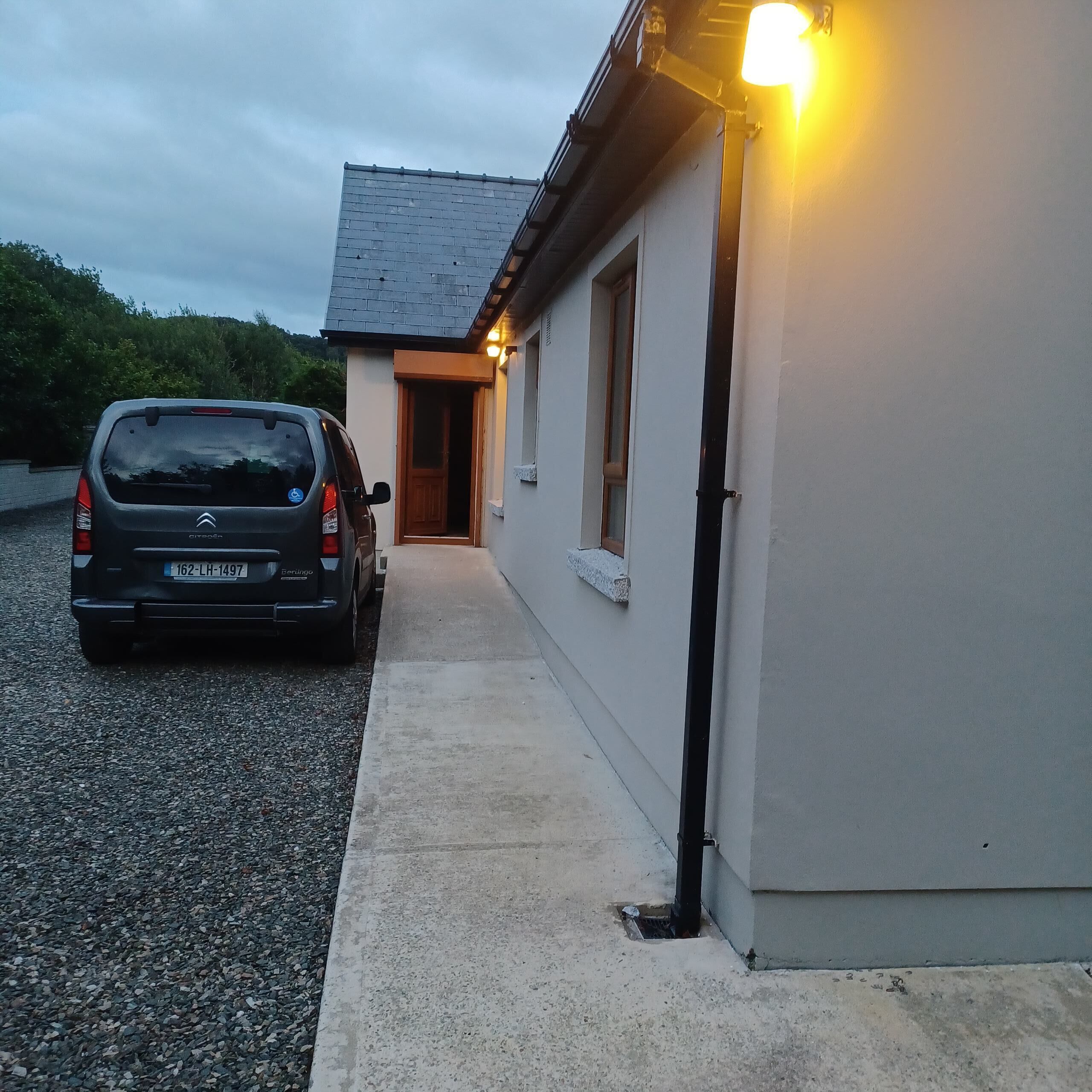 Um carro estacionado em frente a um edifício com um caminho de concreto que leva à entrada.