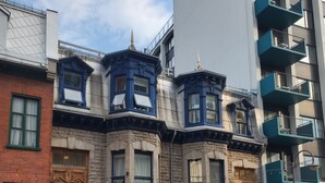 Vista de una calle con un edificio de fachada de piedra, varias ventanas y una entrada tradicional.