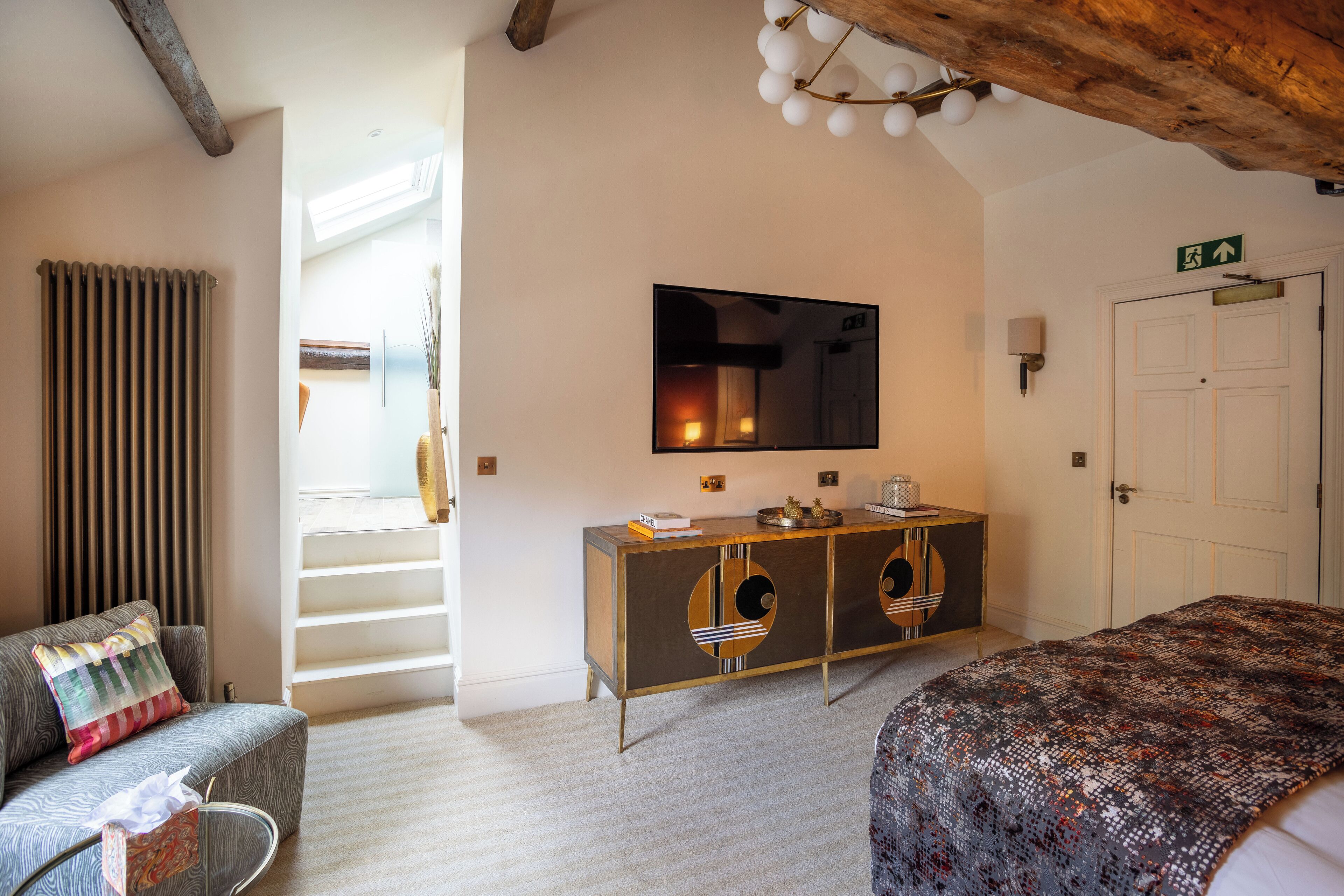 A bedroom with a bed, a sofa, a console table, a mirror, and a door.