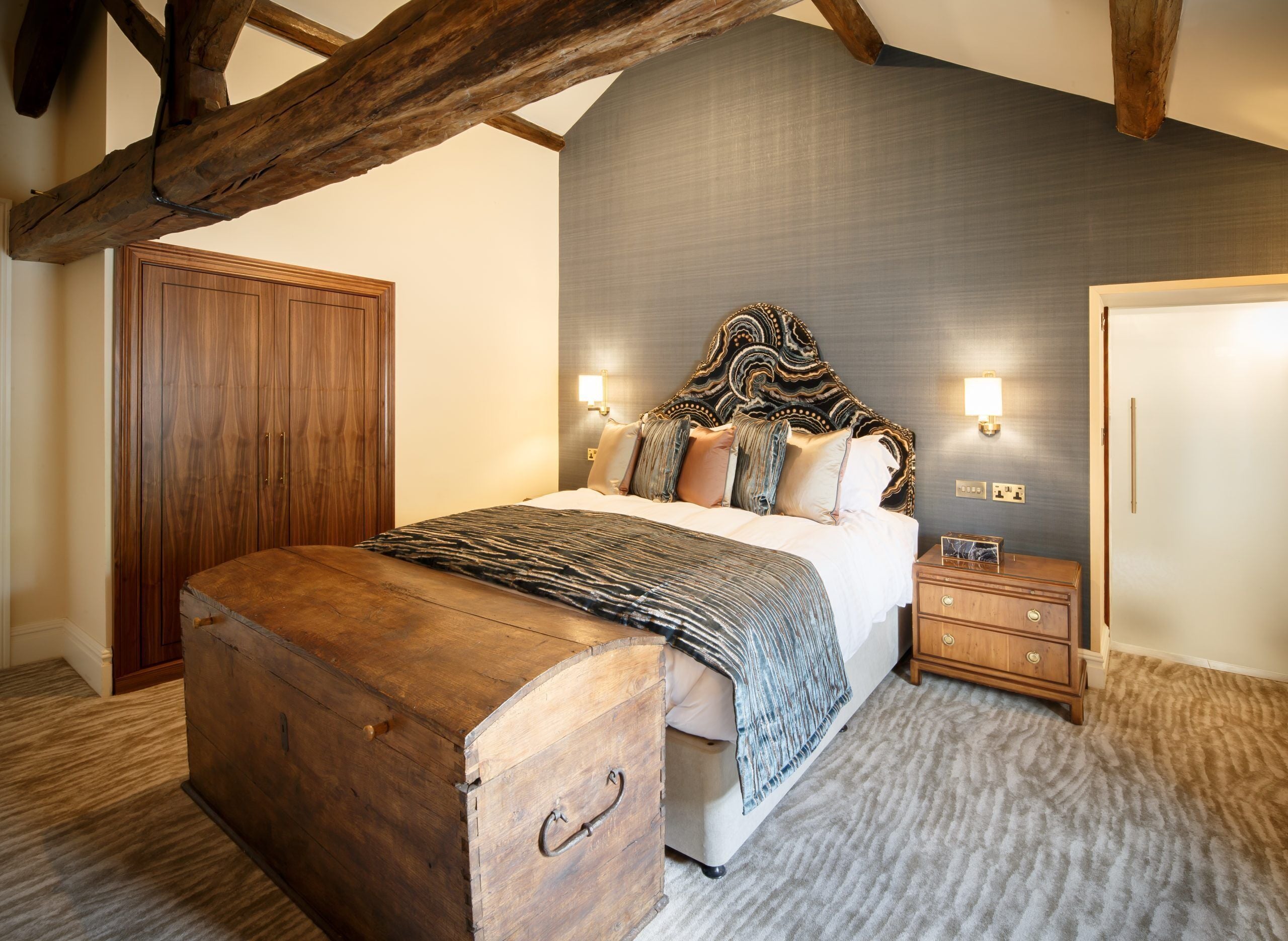 Ein Schlafzimmer mit einem großen Bett, einem Holzkopfteil, zwei Nachttischen und einem Kleiderschrank.