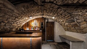 Eine Bar mit Steinwänden, einer Holztresore und einer Sitzbank.