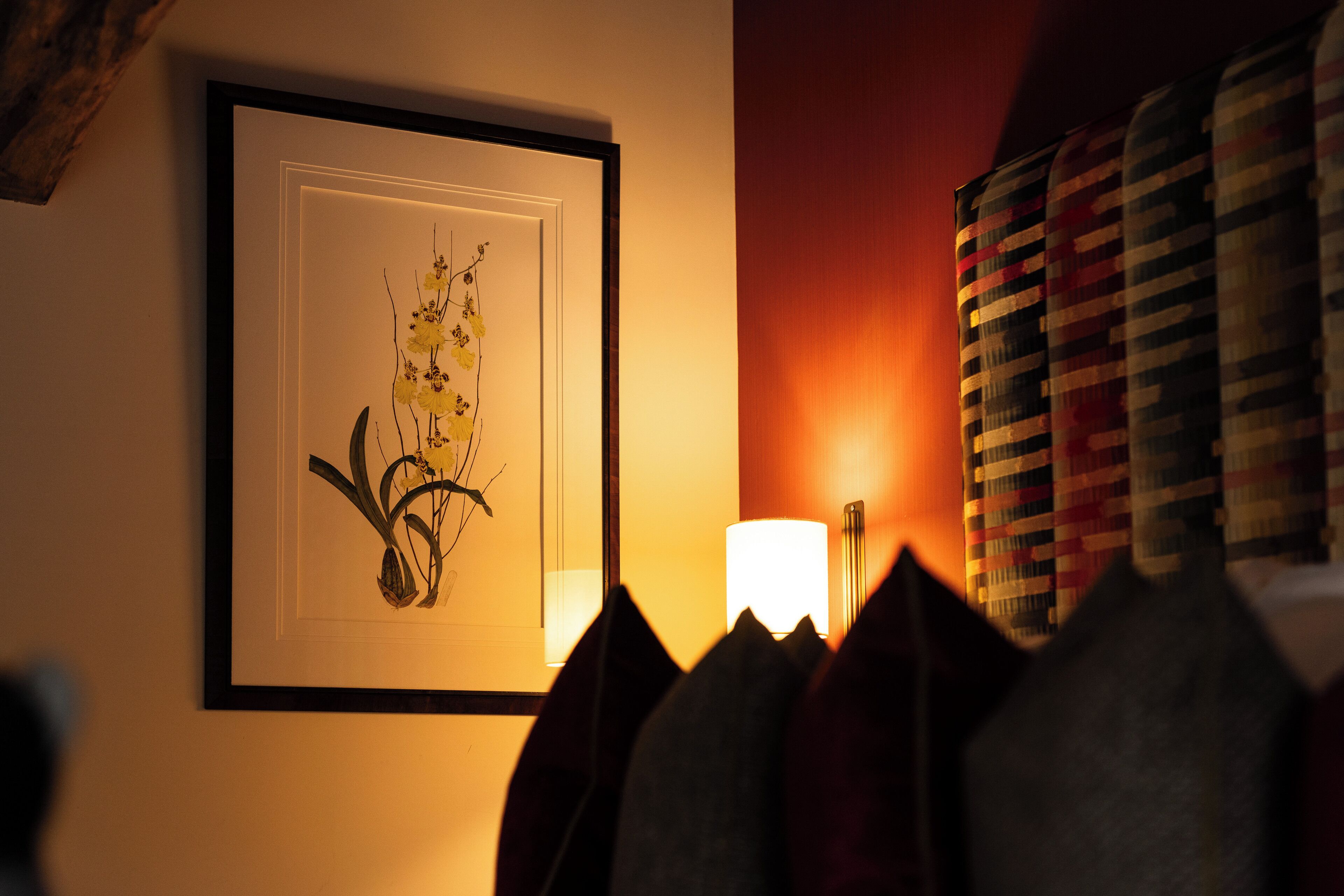 Une œuvre d’art encadrée représentant des fleurs jaunes, accrochée à un mur, un lampadaire et un rideau à motifs.