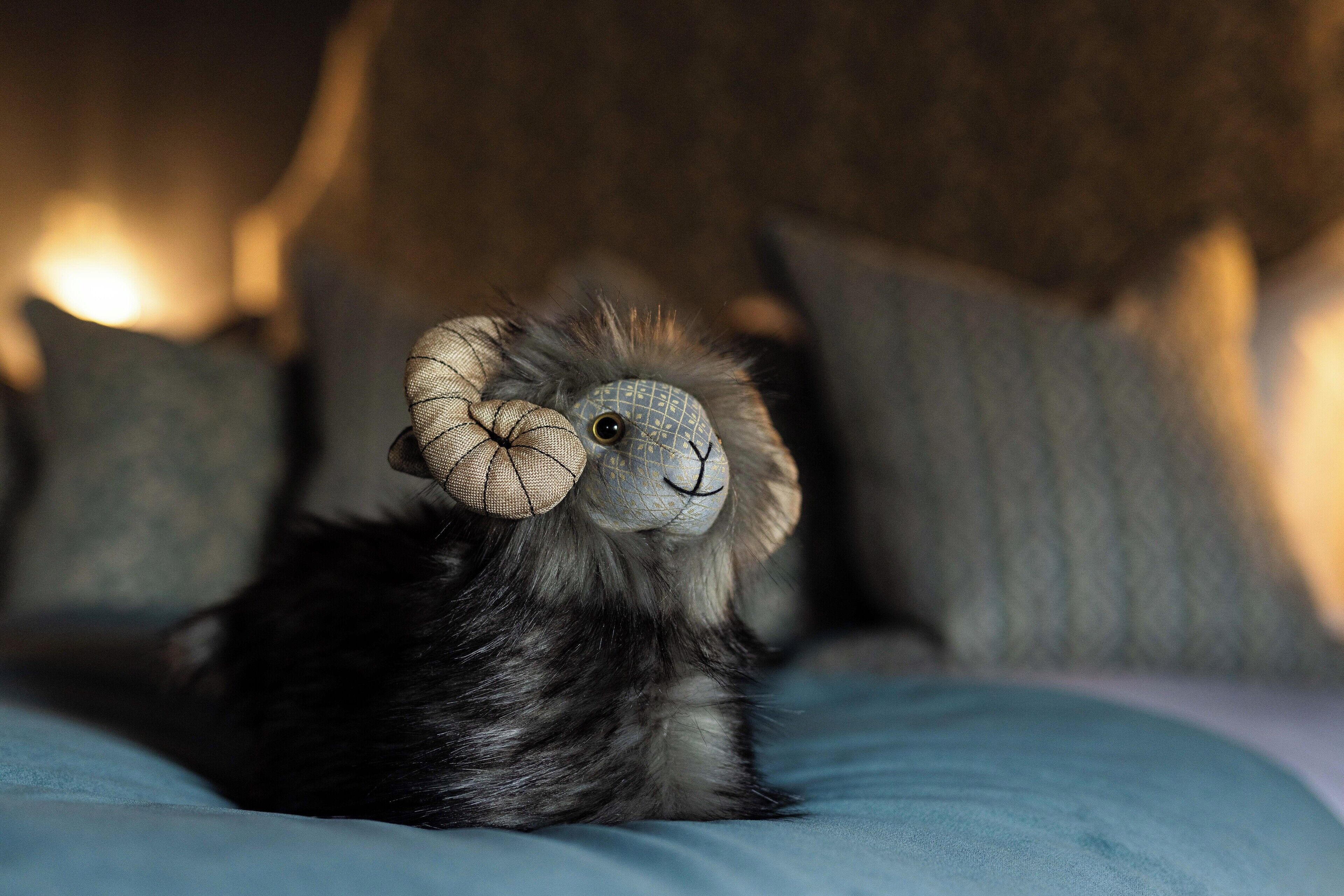 Ein weiches Plüschtier mit großen Hörnern liegt auf einem Bett mit Kissen.