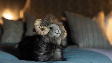 Ein weiches Plüschtier mit großen Hörnern liegt auf einem Bett mit Kissen.