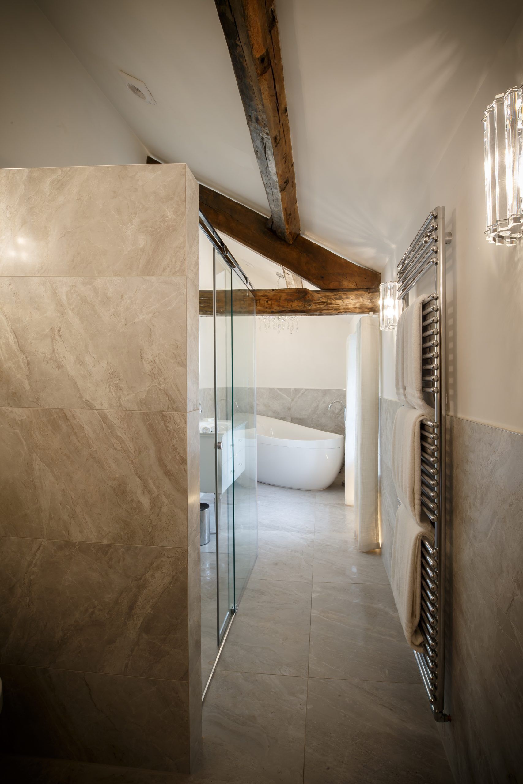 Une salle de bain moderne dotée d’une douche à parois de verre, d’une baignoire sur pied et d’un radiateur fixé au mur.