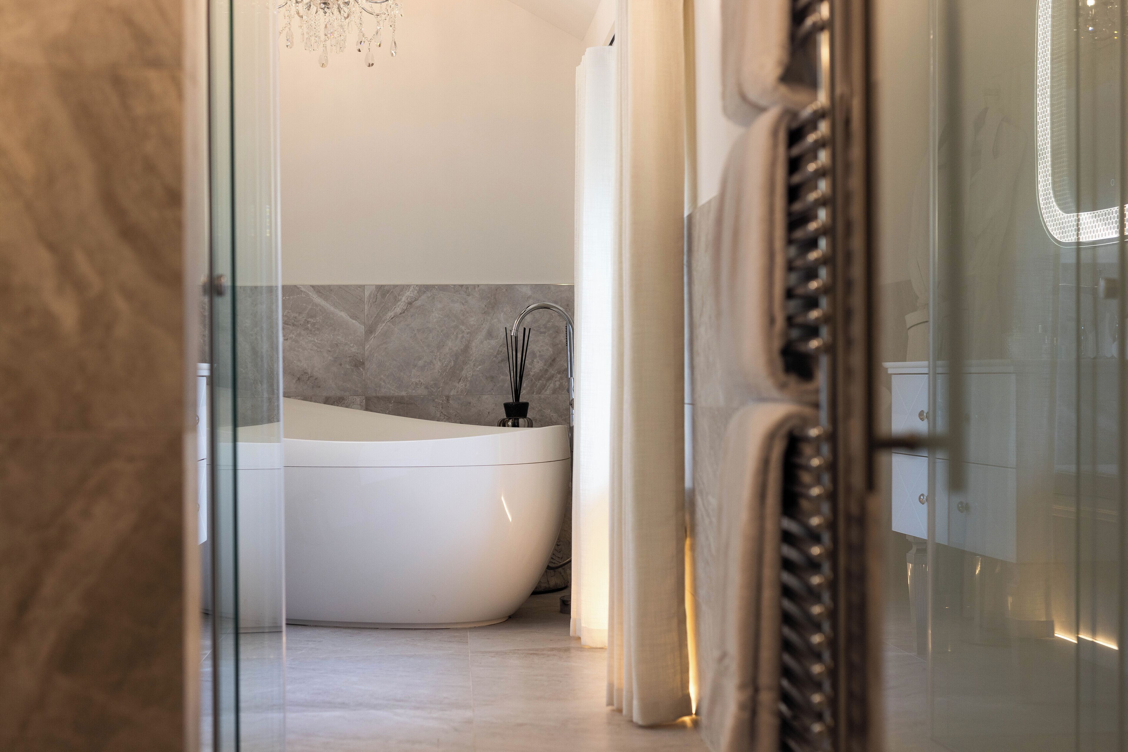 Un baño moderno con una bañera independiente, revestimiento de mármol y cabina de ducha de vidrio.