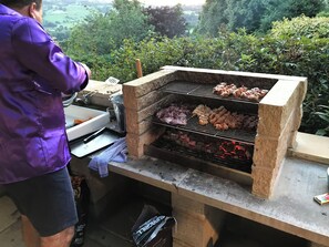 Een barbecue met verschillende vleessoorten die gaar worden, een wastafel en een handdoek op een tafel.