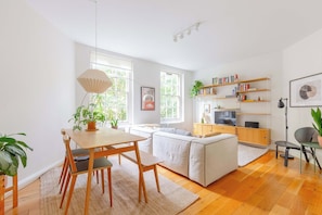 A modern living room with a dining table, sofa, and bookshelves. - Historic 1BD Flat in the Heart of Shoreditch (Greater London)