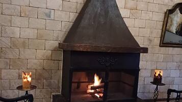 A stone fireplace with a chimney, a wooden bench, and a table with candles.