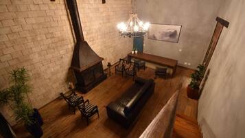 A cozy living room with a fireplace, wooden furniture, and a hanging light fixture.