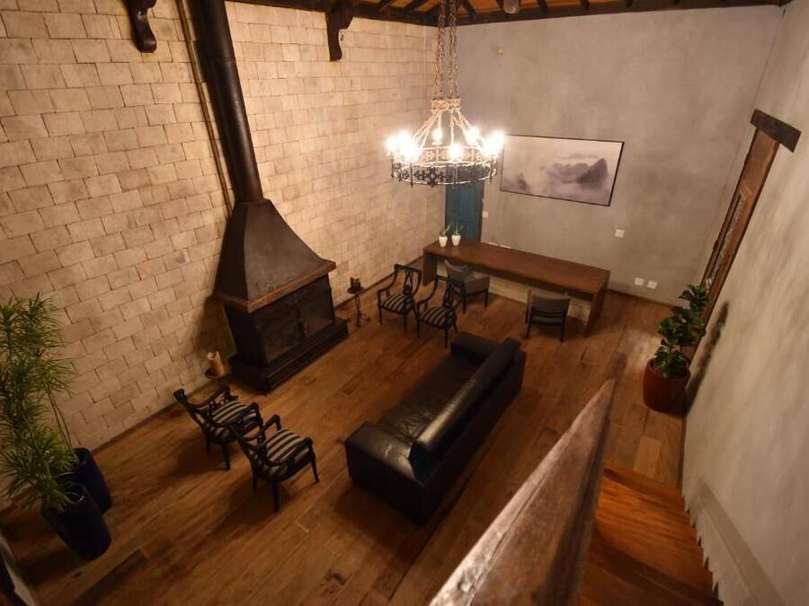 A cozy living room with a fireplace, wooden furniture, and a hanging light fixture.