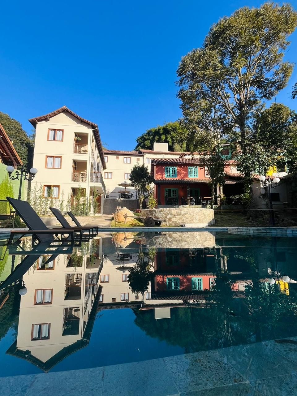 A hotel with a pool, reflecting buildings and trees.