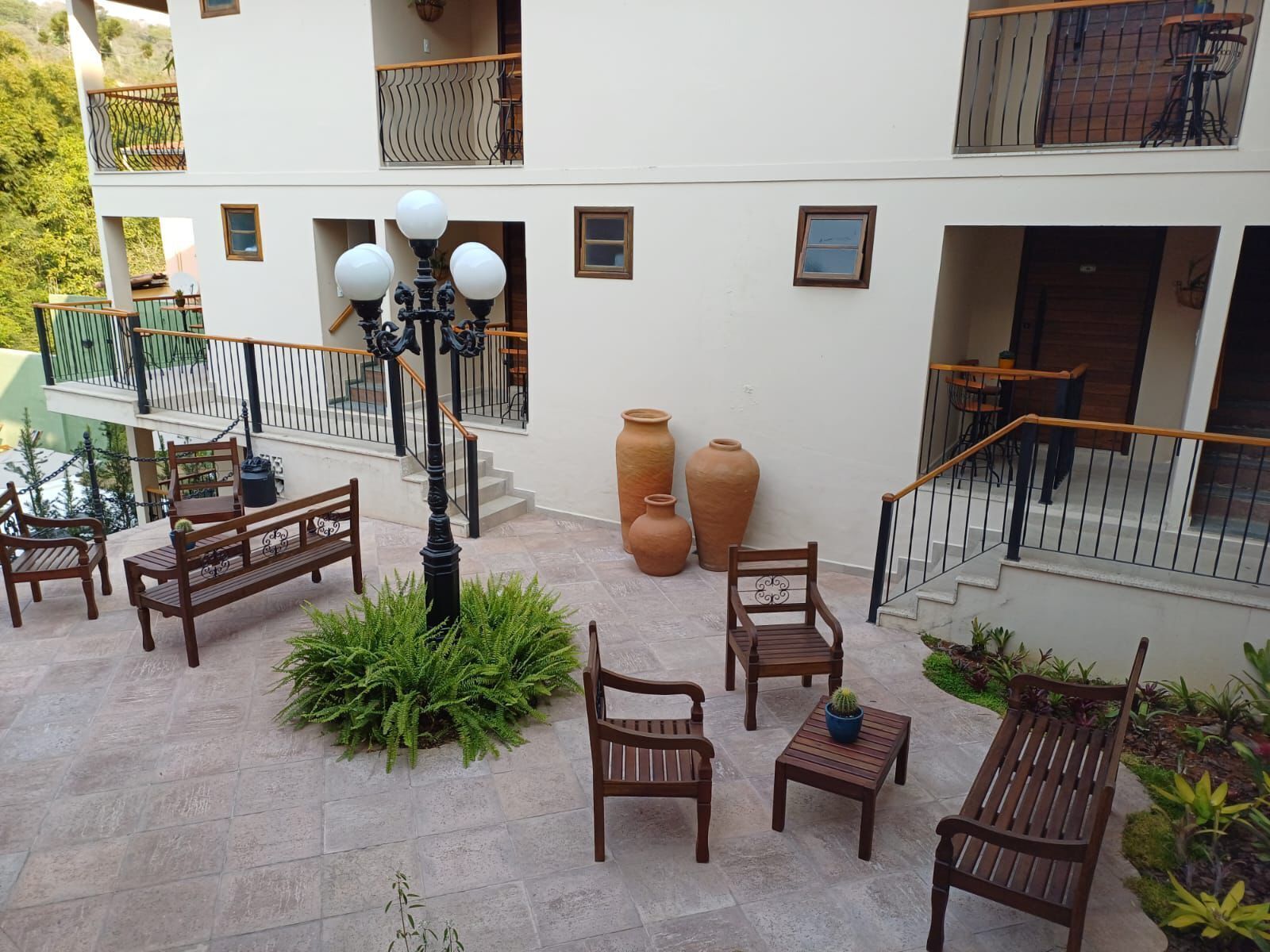 Ein Innenhof mit Sitzgelegenheiten im Freien, einer Treppe und großen Vasen.