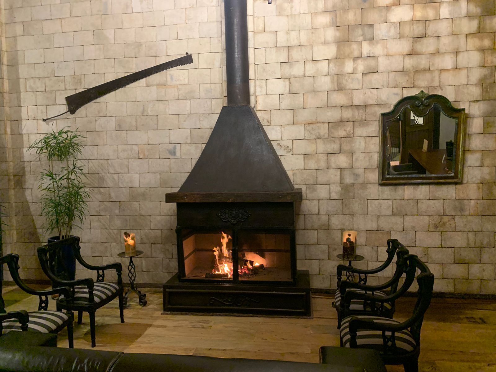 A cozy room with a fireplace, brick walls, and two chairs.
