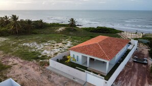 A coastal house with a red-tiled roof, white walls, and a small garden.