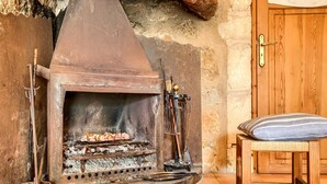 Une cheminée rustique avec une hotte, une porte en bois et un banc.