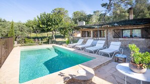 Une piscine rectangulaire à l’eau d’un bleu cristallin, entourée d’escaliers en pierre et de chaises longues blanches.