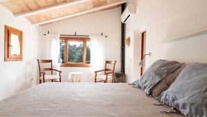 Une chambre à coucher avec un grand lit, deux chaises en bois, une petite table et une fenêtre avec des rideaux.