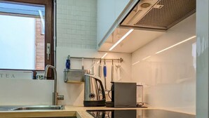 Una cocina moderna con encimera de madera, electrodomésticos de acero inoxidable y un lavamanos a la vista.