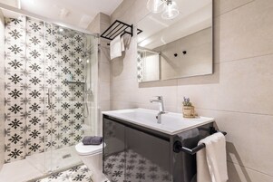 Un bagno moderno con cabina doccia in vetro, un lavandino bianco e uno specchio grande.