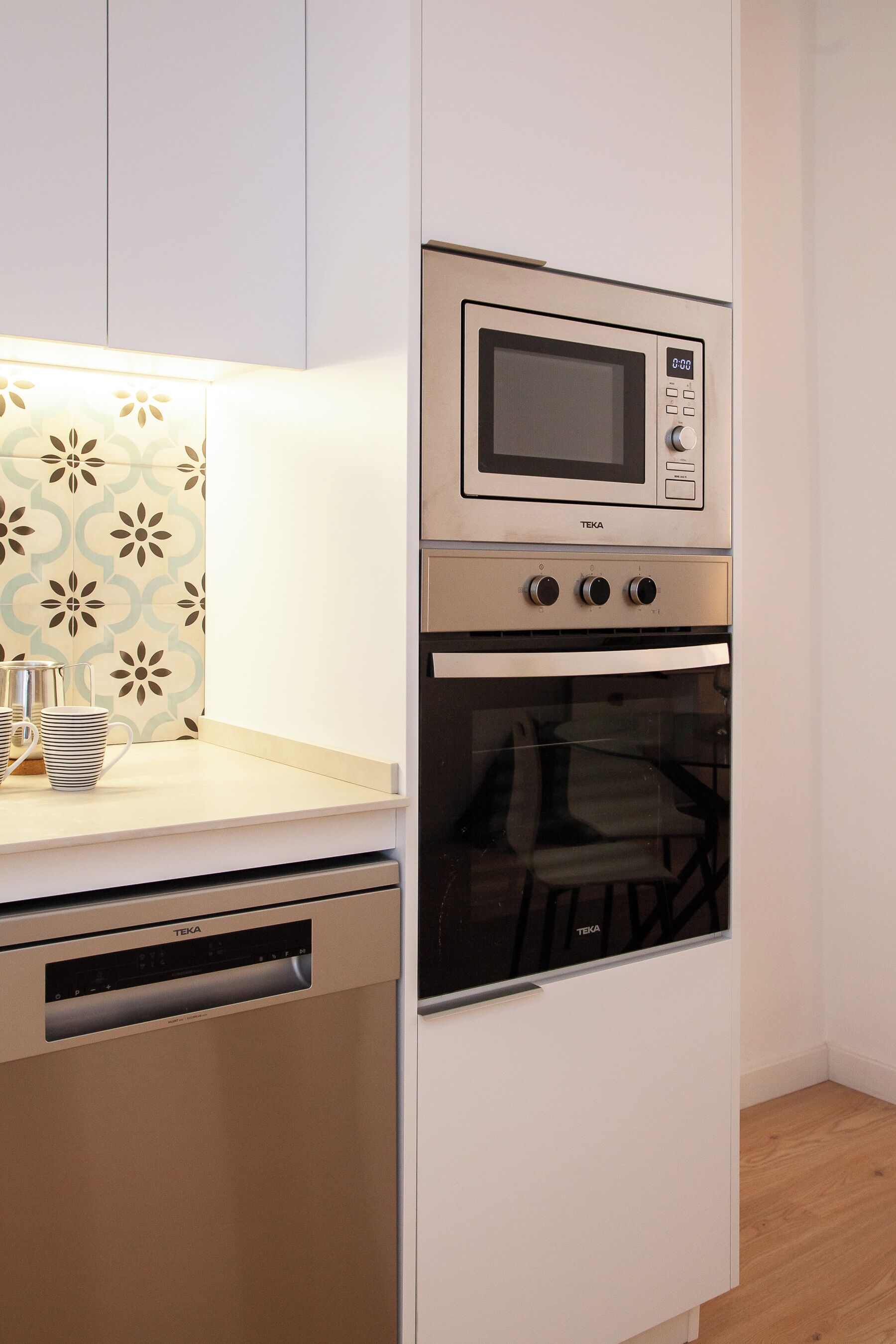 A kitchen with a built-in microwave and oven, a dishwasher, and a patterned backsplash.