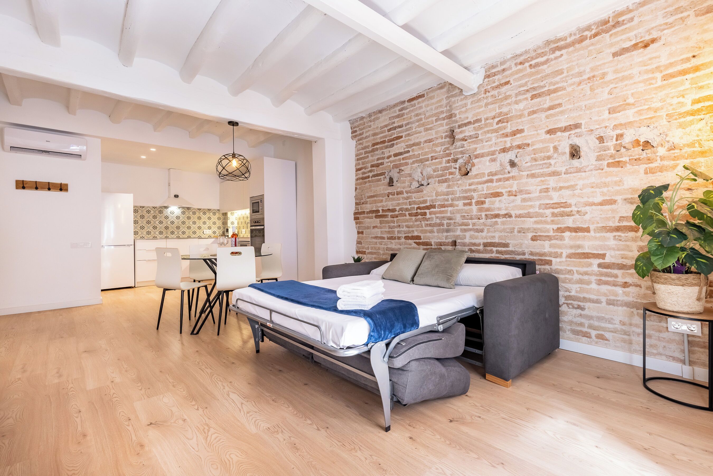 Ein kompakter Wohnraum mit Bett, Sofa, Esstisch und Küchenzeile.