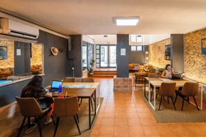 Un hall d’hôtel moderne doté d’un espace salon central, d’un comptoir d’accueil et offrant une vue sur l’extérieur.