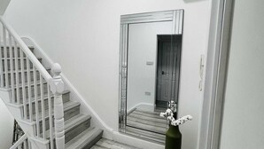 Un escalier avec des rampes blanches et des marches en bois menant à un mur recouvert de miroirs.