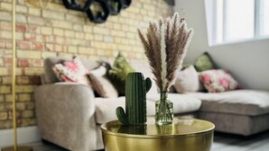 Un salon moderne avec un mur en briques, un canapé et un vase décoratif posé sur un plancher en bois.