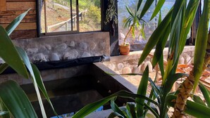 A room with a large window, a stone bench, and a potted plant. - Lodge Colbun (Colbún)