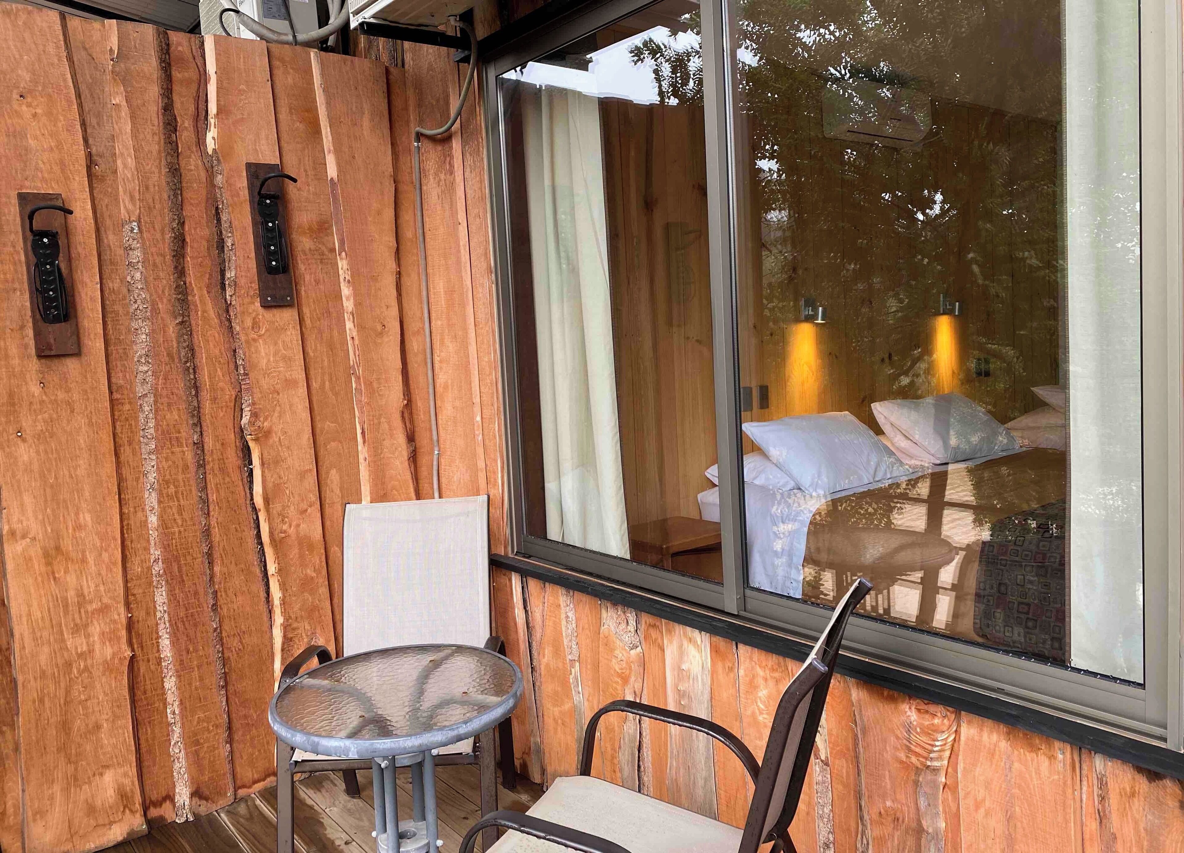 A wooden exterior wall with a glass door leading to a bedroom.