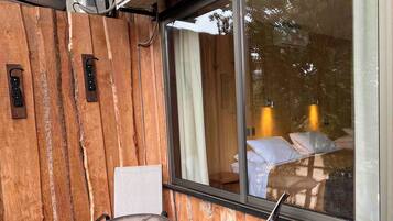 A wooden exterior wall with a glass door leading to a bedroom.