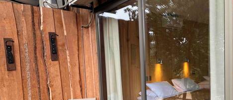 A wooden exterior wall with a glass door leading to a bedroom.