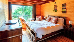 A wooden cabin bedroom with a bed, a desk, and a chair. - Lodge Colbun (Colbún)