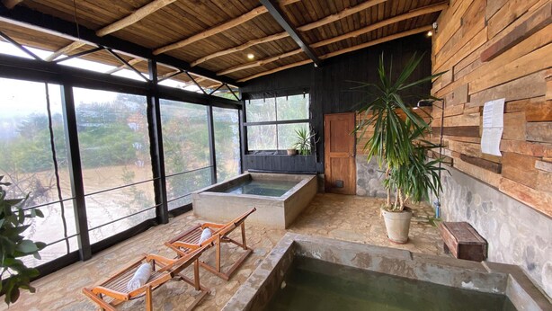 A spa area with wooden beams, a hot tub, and two wooden loungers. - Lodge Colbun (Colbún)