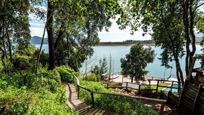 A wooden staircase leading to a beach area with a view of the water and distant mountains. - Lodge Colbun (Colbún)