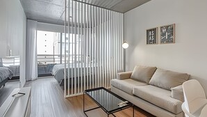 A modern living room with a glass coffee table, a beige sofa, and a white partition. - 802 Very bright studio apartment in Belgrano (CABA)