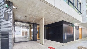 A modern building entrance with a glass door, a concrete pillar, and a black facade. - 802 Very bright studio apartment in Belgrano (CABA)