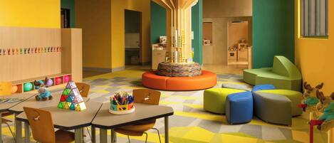 Un cuarto de juegos infantil, luminoso y lleno de color, con una mesa, sillas y unidades de almacenamiento coloridas.