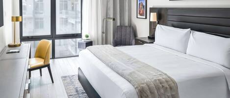 Ein modernes Hotelzimmer mit einem großen Bett, einem Schreibtisch, einem Stuhl und Blick auf Gebäude durch das Fenster.