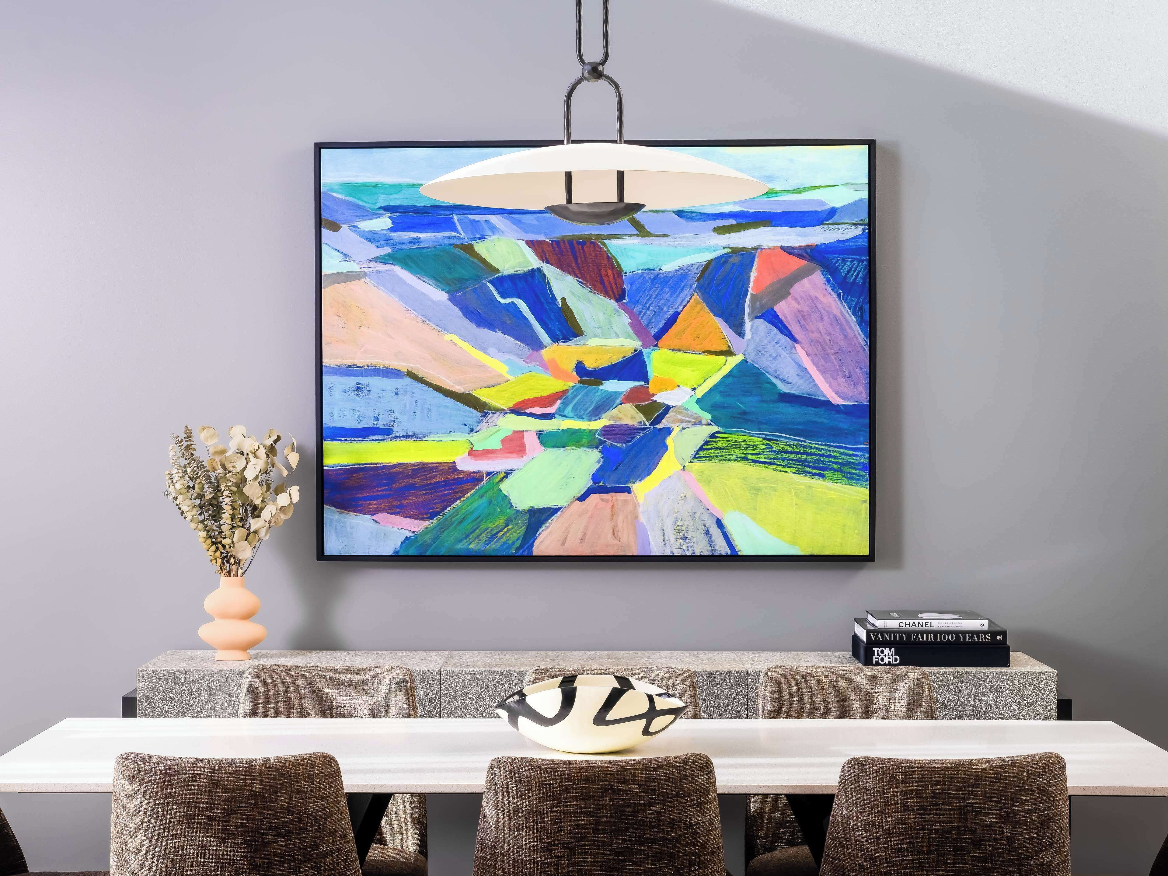 A dining area with a modern table, chairs, and a colorful abstract painting on the wall.