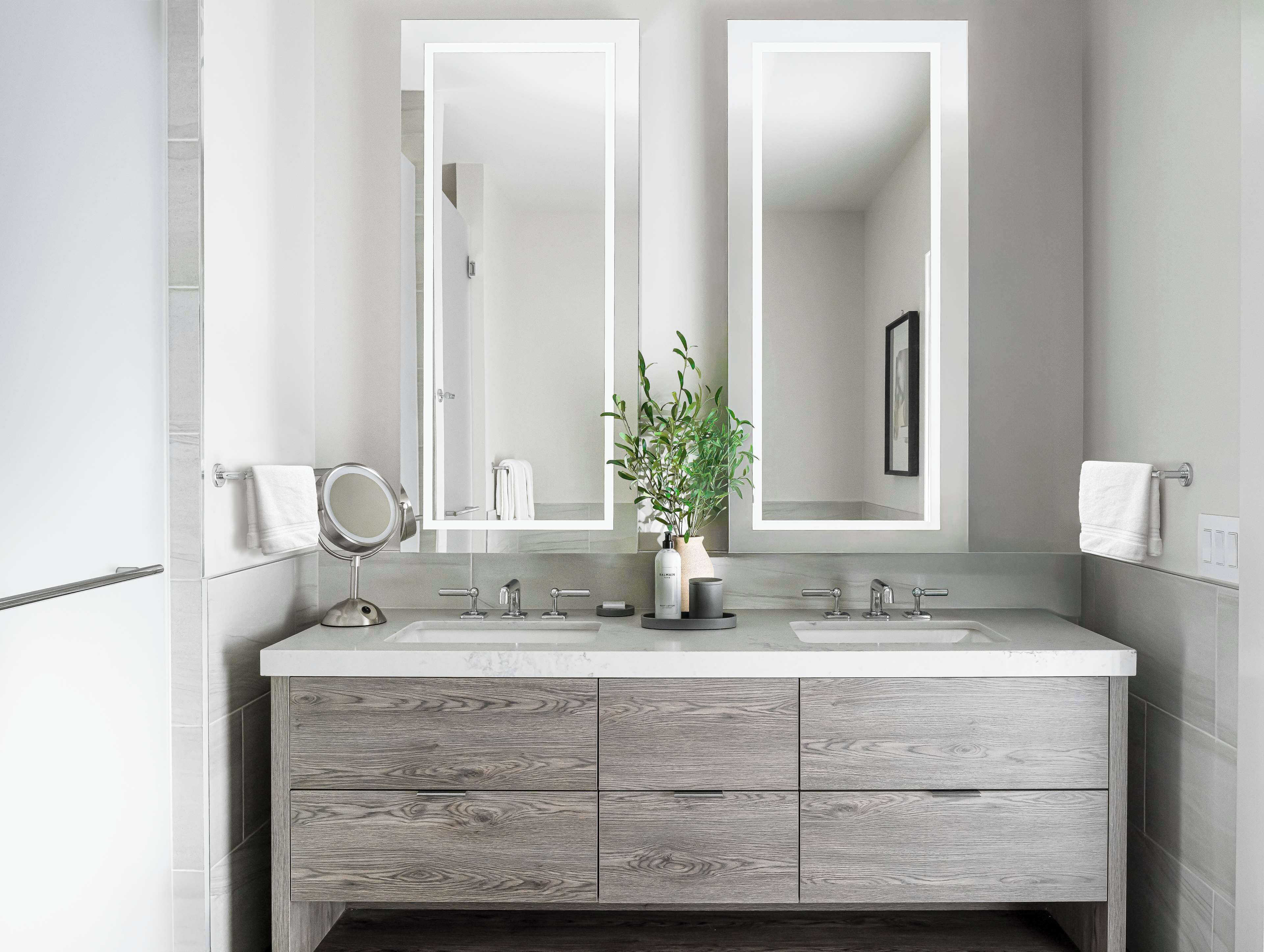 Un baño moderno con dos lavamanos, un espejo grande y una planta en maceta.