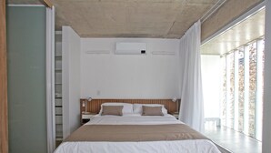 A modern hotel room with a large bed, a built-in air conditioning unit, a bedside table with a lamp, and a view of the outdoors through large windows. - "Tu Hogar Temporal en Belgrano" (Ciudad Autónoma de Buenos Aires)