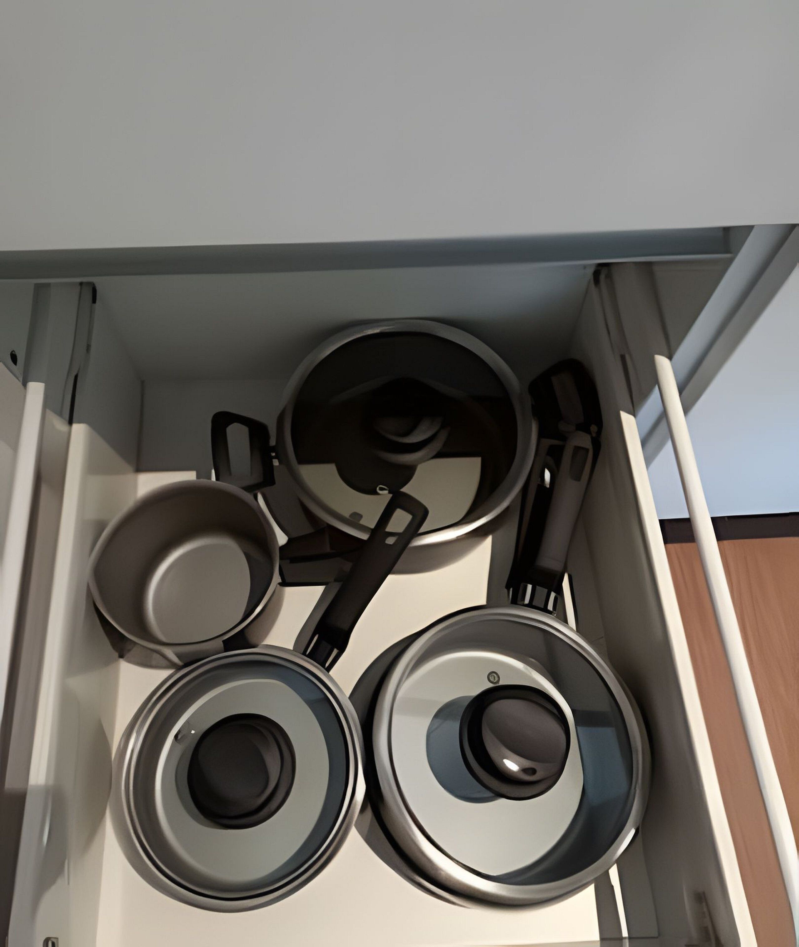 Un cajón de cocina con cuatro ollas y sartenes.
