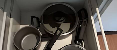 A kitchen drawer with four pots and pans.