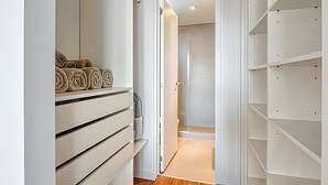 En hall med en inbyggd garderob som har flera lådor och hyllor, och som leder vidare till ett badrum med en duschhörna.