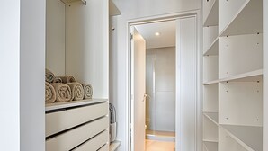 Ein begehbarer Kleiderschrank mit offenen Regalen und einem aufgerollten Teppich auf der linken Seite.
