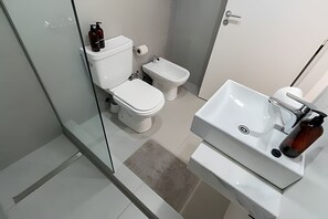 Enjoy a refreshing shower in the bathroom, featuring a shower enclosure, toilet, bidet, and sink with a faucet.