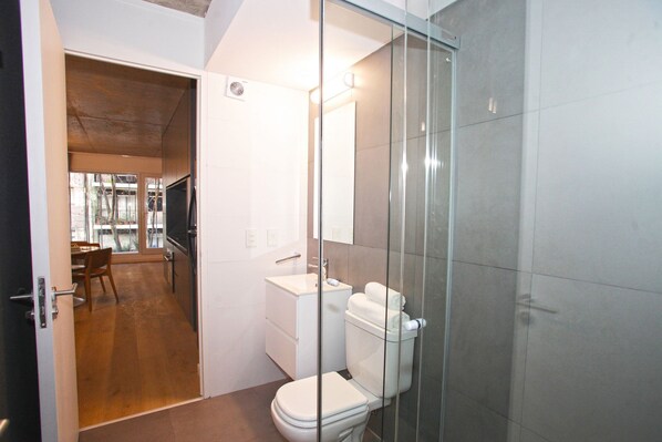 A modern bathroom with a glass shower enclosure, a white toilet, and a sink. - "Your Temporary Home in Belgrano" (Ciudad Autónoma de Buenos Aires)
